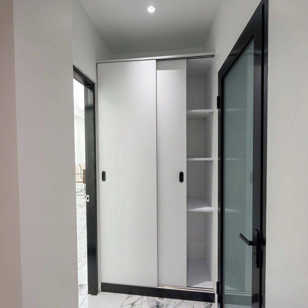 Un placard moderne à portes coulissantes, doté d’une porte en verre, d’un sol en marbre et d’un éclairage encastré au plafond.