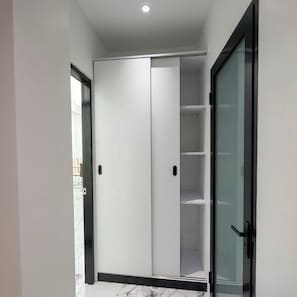 A modern sliding closet with a glass door, a marble floor, and a recessed ceiling light. - Sun On the Hill Villa by Betterplace (Nusa Dua)