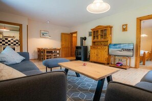 A living room with a sofa, a wooden coffee table, and a television. - Ground floor in the Reimer house (ID 312) (St. Peter-Ording)