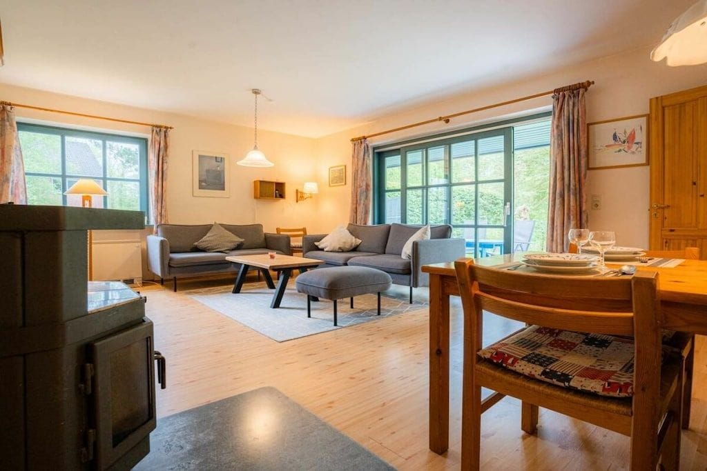 Ein gemütliches Wohnzimmer mit einer Couch, einem Hocker und einem Esstisch für zwei Personen.