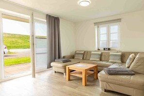 Ein modernes Wohnzimmer mit einer Couch, einem Couchtisch und einer Schiebetür zu einem Balkon.