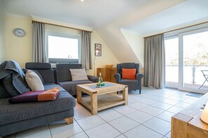 Ein modernes Wohnzimmer mit Sofa, Sessel und Couchtisch.