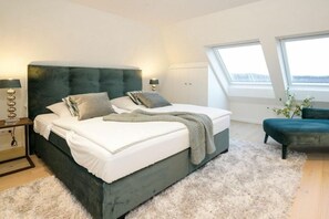 Ein Schlafzimmer mit einem großen Bett, einem Nachttisch, einer Lampe, einem Fenster und Blick ins Freie.