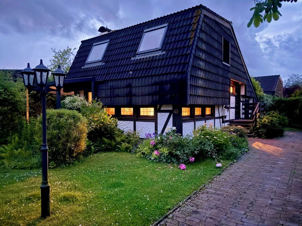 Ein traditionelles Haus mit schrägem Dach, einem sichtbaren Dachfenster und einem Ziegelweg, der zum Eingang führt.