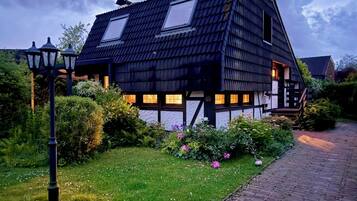 Ein traditionelles Haus mit schrägem Dach, einem sichtbaren Dachfenster und einem Ziegelweg, der zum Eingang führt.