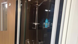 Une salle de bain moderne avec une douche à parois de verre, un lavabo blanc et un miroir.