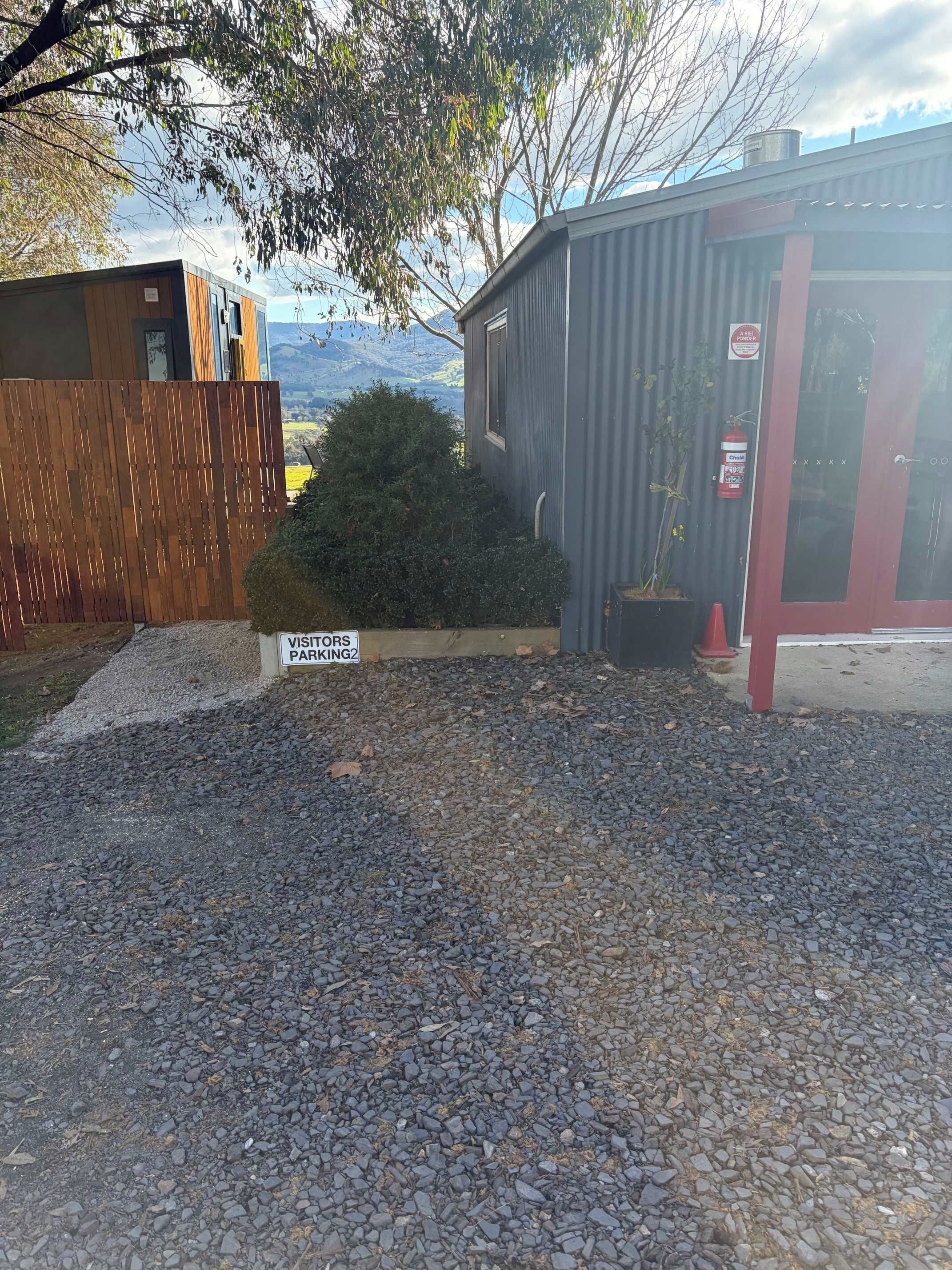 A gravel driveway leading to a building with a sign indicating parking.