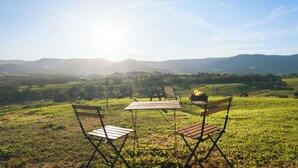 Un espace extérieur aménagé avec une pelouse, une table et des chaises, un foyer et une vue panoramique sur des collines et des montagnes.
