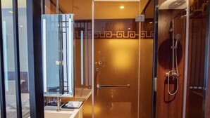 Un baño con cabina de ducha de vidrio, tocador de madera y un espejo.