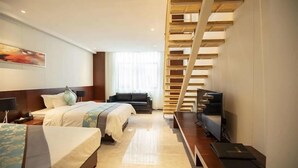 Una habitación de hotel con cama, sofá, televisión y una escalera.