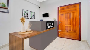 A hotel reception desk with a 'HOTEL' sign, a flat-screen TV, and framed artwork on the wall. - Townhouse Valiyavila Bus Terminal (Trivandrum)