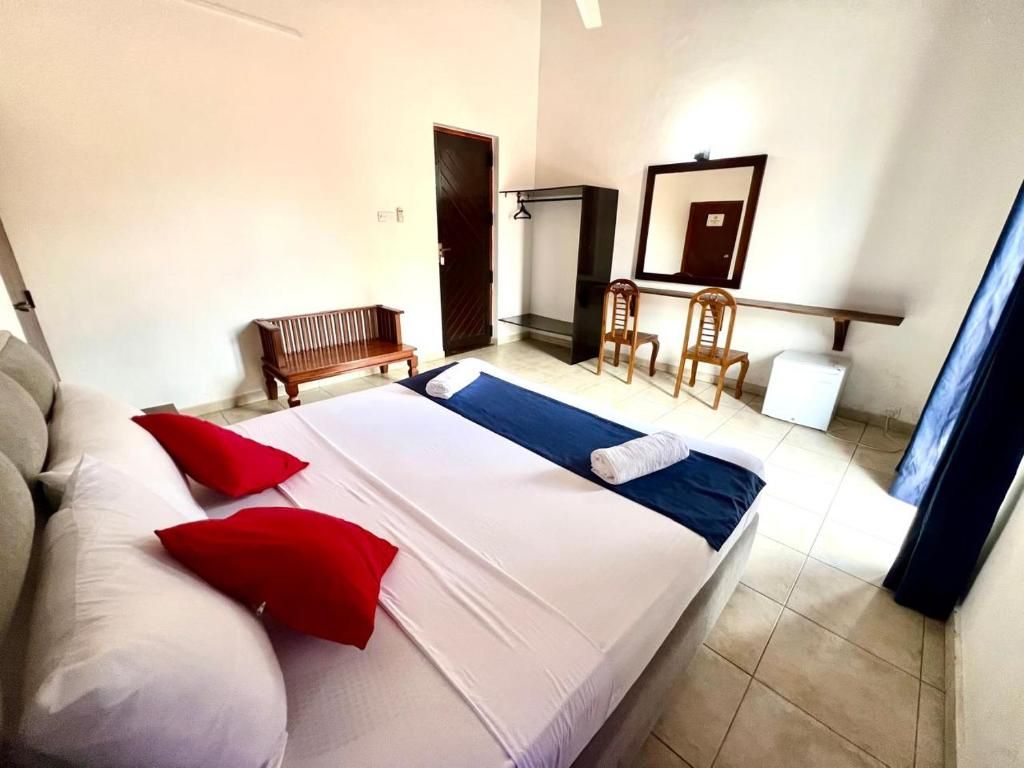 Una habitación de hotel con una cama, un banco, una silla, un escritorio y un espejo.