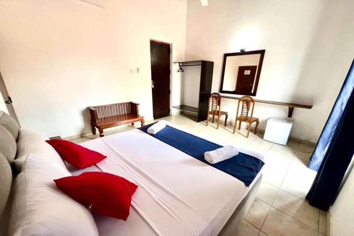 Ein Hotelzimmer mit Bett, Sitzbank, Stuhl, Schreibtisch und Spiegel.