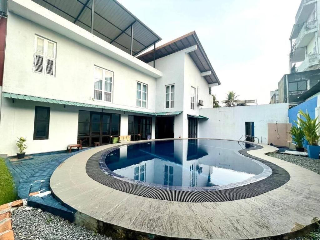 Una casa moderna con piscina circular, un porche cubierto y un ventanal grande.