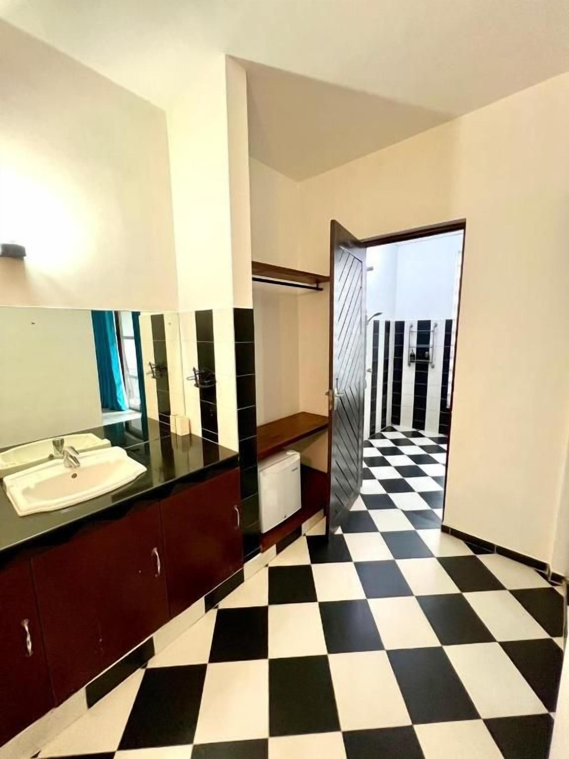 Un baño con piso a cuadros, un lavamanos y un espejo.