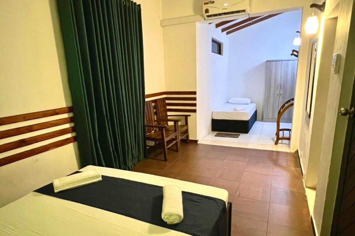 Ein Hotelzimmer mit Bett, Sessel, kleinem Tisch und einem durchgegangenen Tür sichtbaren Badezimmer.