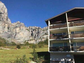 A multi-story building with balconies, set against a mountainous backdrop. - Residenz Belair Leukerbad # 4-bed apartment, Bad, WC by Interhome (Leukerbad)