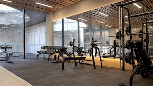 Une salle de sport équipée de divers appareils d’exercice, dotée de grandes fenêtres et d’un design moderne au niveau du plafond.