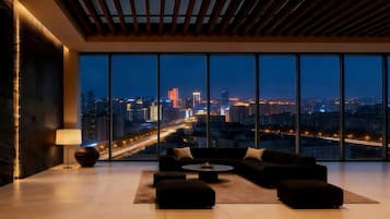 Uma sala de estar moderna com uma janela ampla de frente para uma vista urbana noturna.