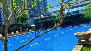 Una piscina con agua cristalina azul, rodeada de césped y árboles.