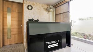 Un comptoir d’accueil avec une enseigne indiquant « TOWNHOUSE », une porte en bois et un mur orné d’un motif.