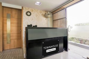 A reception desk with a 'TOWNHOUSE' sign, a wooden door, and a patterned wall. - Townhouse Kranti Square Aurangabad (Aurangabad)