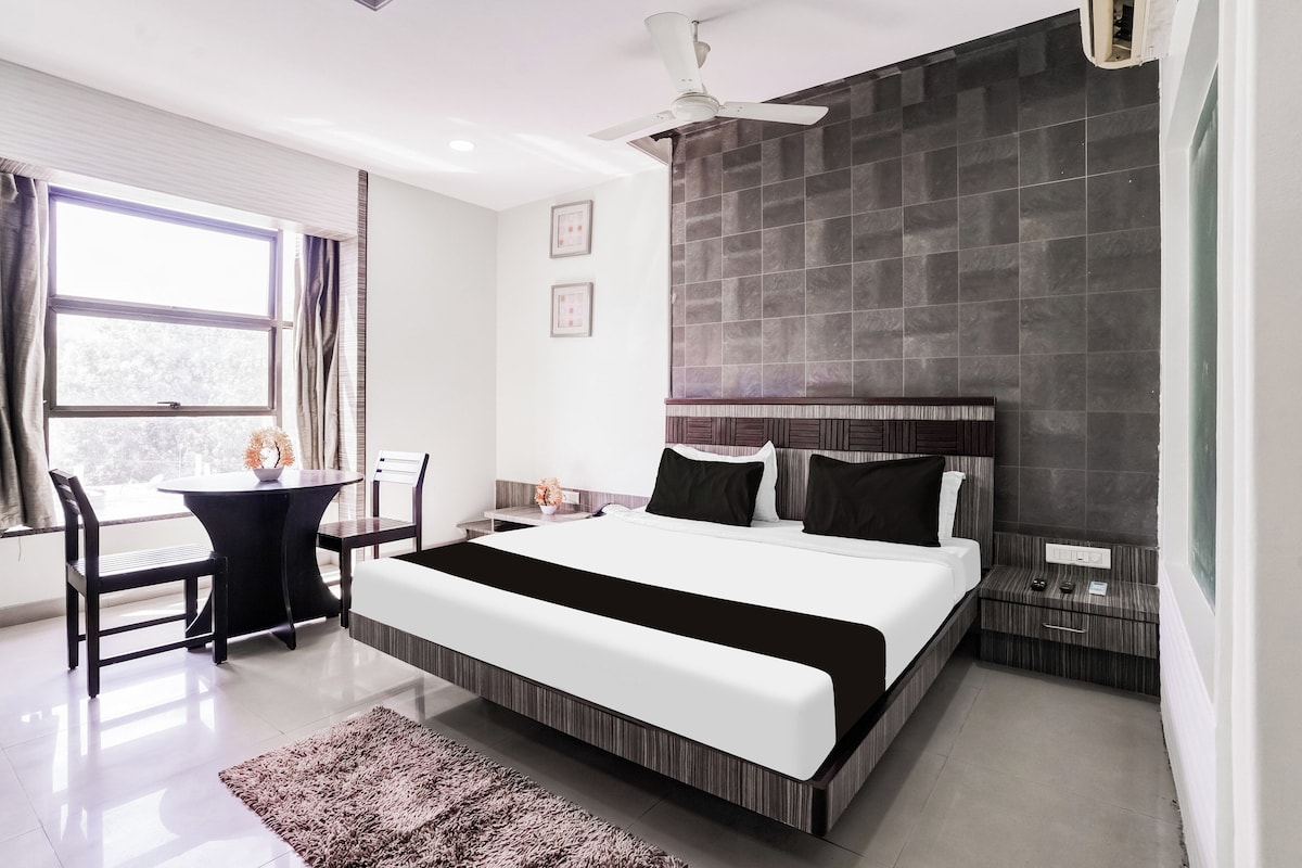 A modern hotel room with a large bed, a desk, and a chair.