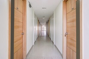 A corridor with wooden doors, each marked with a number, leading to individual rooms.