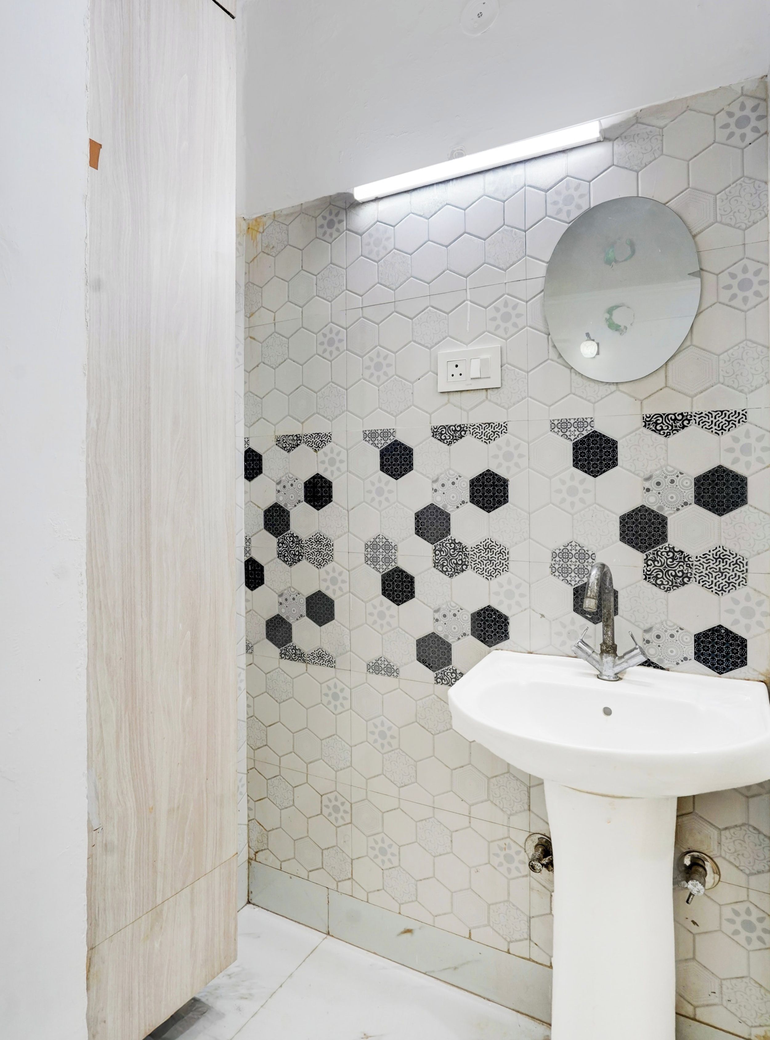A bathroom with a white sink, a mirror, and a hexagonal patterned wall.