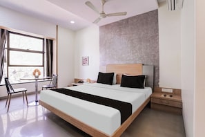 A hotel room with a bed, a desk with a chair, a ceiling fan, and a window with curtains. - Townhouse Kranti Square Aurangabad (Aurangabad)
