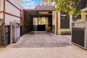 A covered entrance with a metal gate, a concrete floor, and a staircase leading to a building.