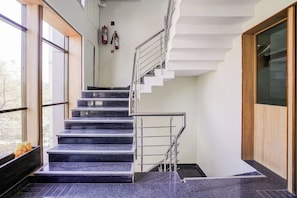 A modern staircase with a metal railing, leading to a landing with a wooden door.
