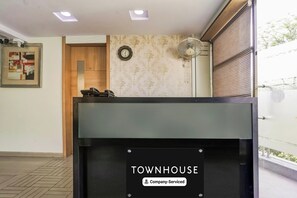A reception desk with a sign reading 'TOWNHOUSE Company-Serviced.' - Townhouse Kranti Square Aurangabad (Chhatrapati Sambhajinagar)