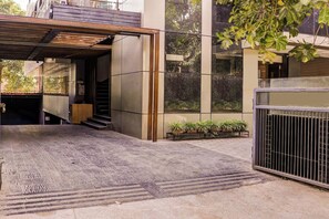 A modern building with a covered entrance, a staircase leading to an upper level, and a security sign. - Townhouse Kranti Square Aurangabad (Chhatrapati Sambhajinagar)