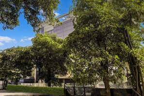 Een gebouw in moderne architectuur, omringd door weelderige groene bomen en een heldere blauwe lucht.