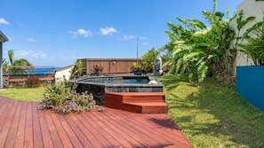 A backyard with a hot tub, wooden deck, and tropical plants. - Villa Acazou – A Getaway with a Pool and Ocean View (Saint-Leu)