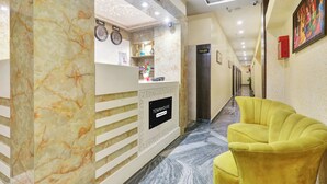 A hotel reception area with a marble reception desk, a clock, and a reception sign.