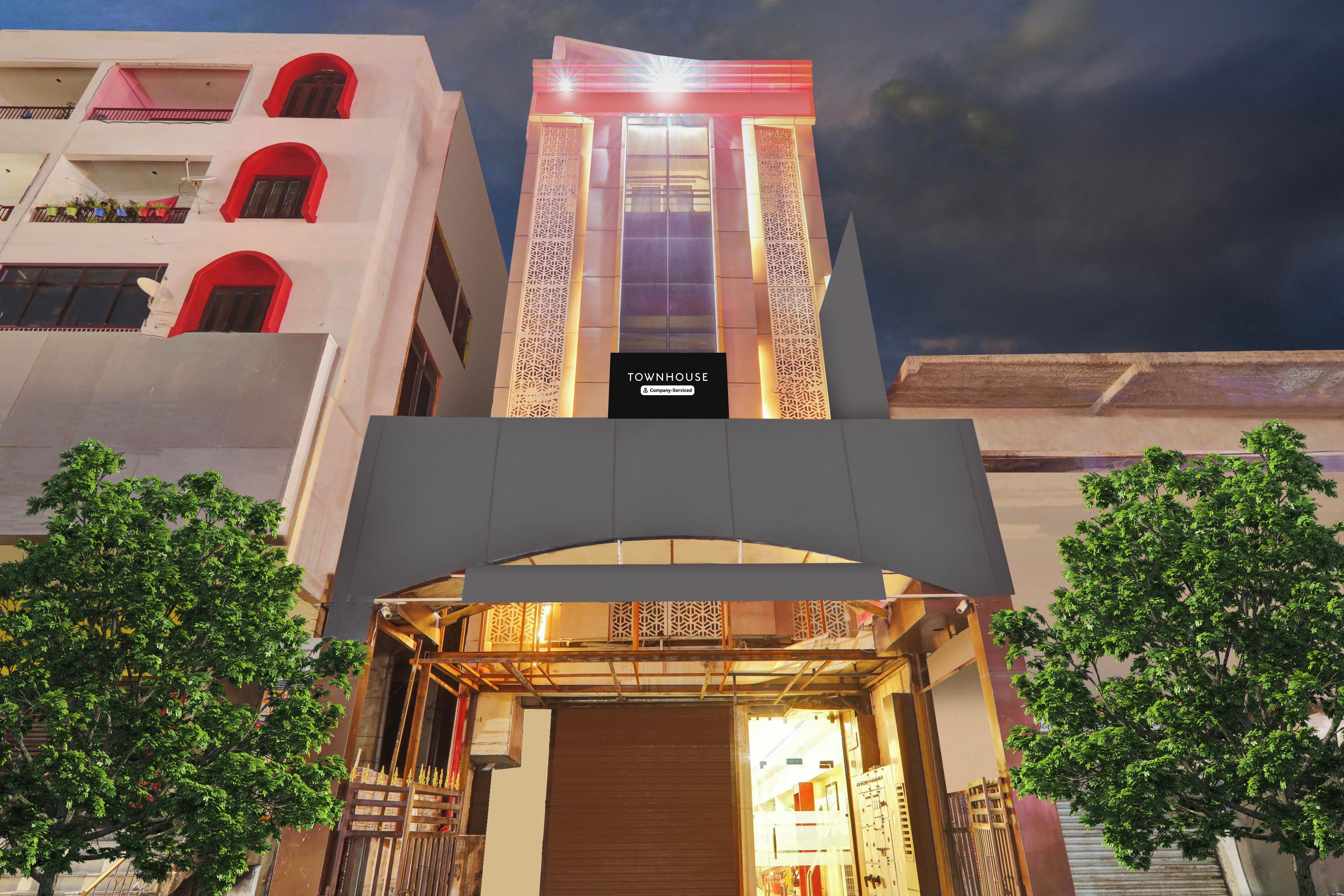 A modern building with a prominent entrance, a sign indicating it's a serviced company property, and a view of the interior through the entrance.