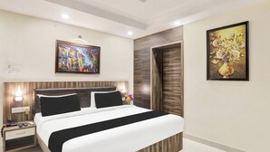 A modern hotel room with a large bed, a nightstand with a phone, and two paintings on the walls.