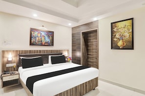 Una habitación de hotel moderna con una cama grande, una mesita de noche con teléfono y dos cuadros en las paredes.