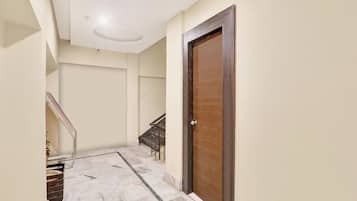 Un pasillo con una puerta de madera, una escalera y un suelo de mármol.