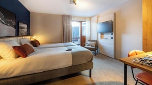 A hotel room with two beds, a desk, a chair, a television, and a window with curtains. - Belambra Club Les Saisies - Les Embrunes - Winter & Summer (Villard-sur-Doron)