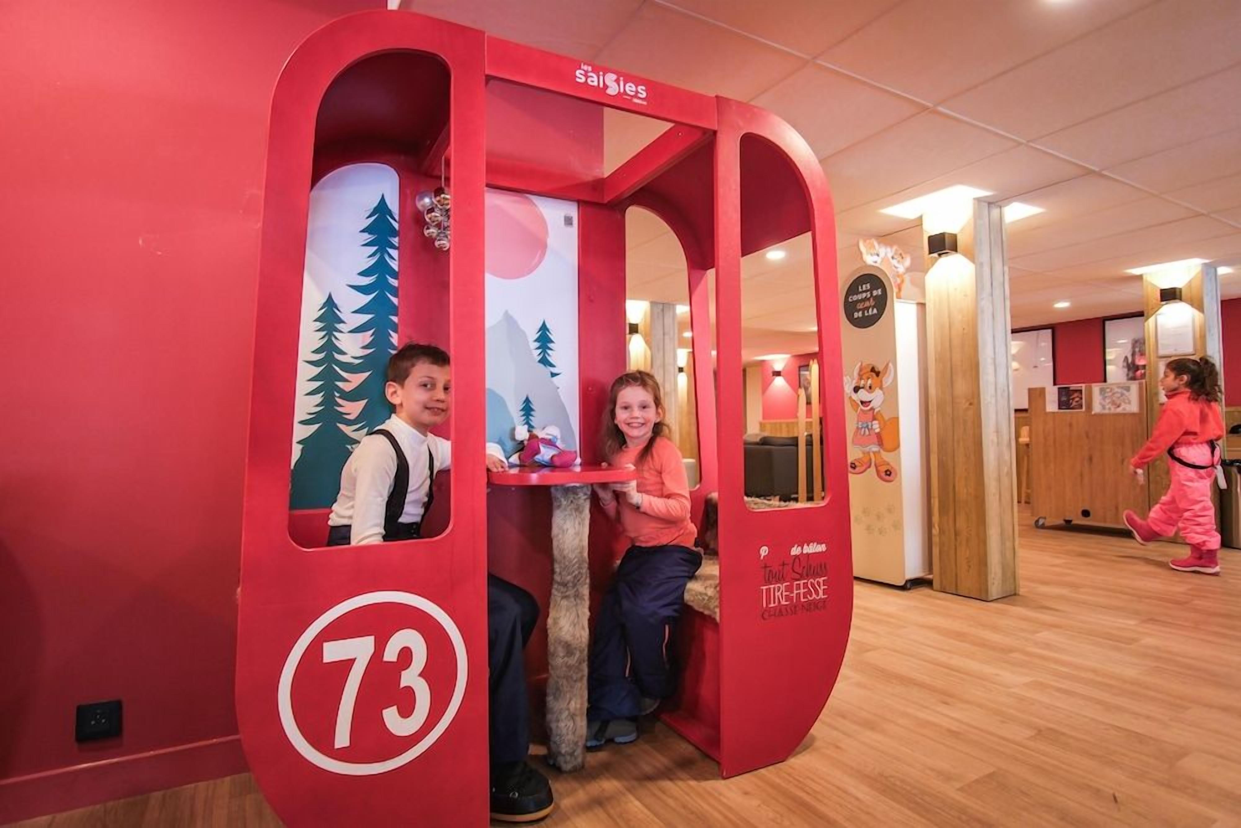 Un espace de jeux pour enfants avec une structure rouge, portant le numéro 73, et une pancarte sur laquelle on peut lire « la saisie ».