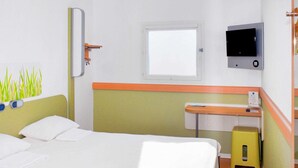 A hotel room with a bed, a bedside table, a television, and a window. - Ibis Budget Flers Grands Champs (Flers)