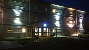 A multi-story hotel with a flat facade, large windows, and a parking lot.