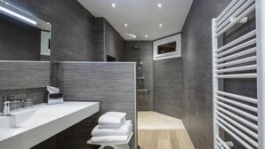 Un baño moderno con un espejo grande, un lavabo blanco, un perchero para toallas y una zona de ducha.