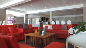 A modern interior with red sofas, a wooden coffee table, and white chairs. - Vvf Villages Parent (Parent)