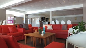 A modern interior with red sofas, a wooden coffee table, and white chairs. - Vvf Villages Parent (Parent)