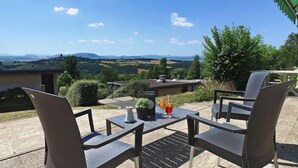 A patio with two chairs and a table, overlooking a scenic landscape with hills and a body of water. - Vvf Villages Parent (Parent)