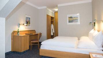 A hotel room with a bed, a desk, a chair, and a wardrobe.
